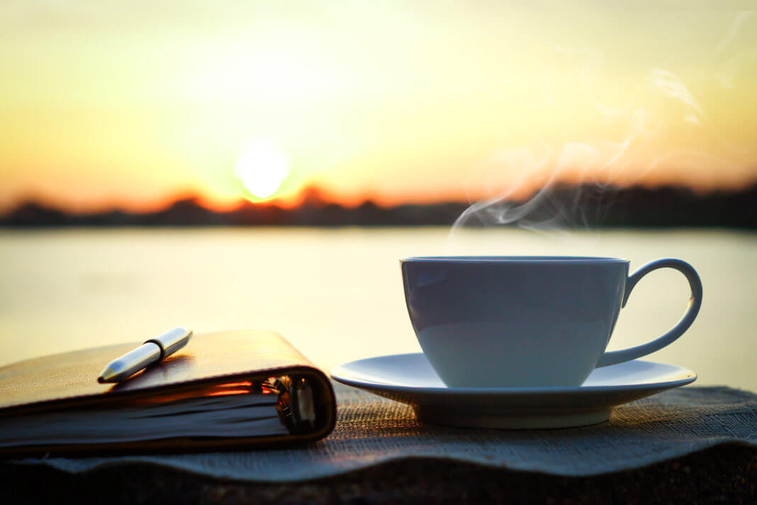 Cup of coffee and a notebook as the sun rises